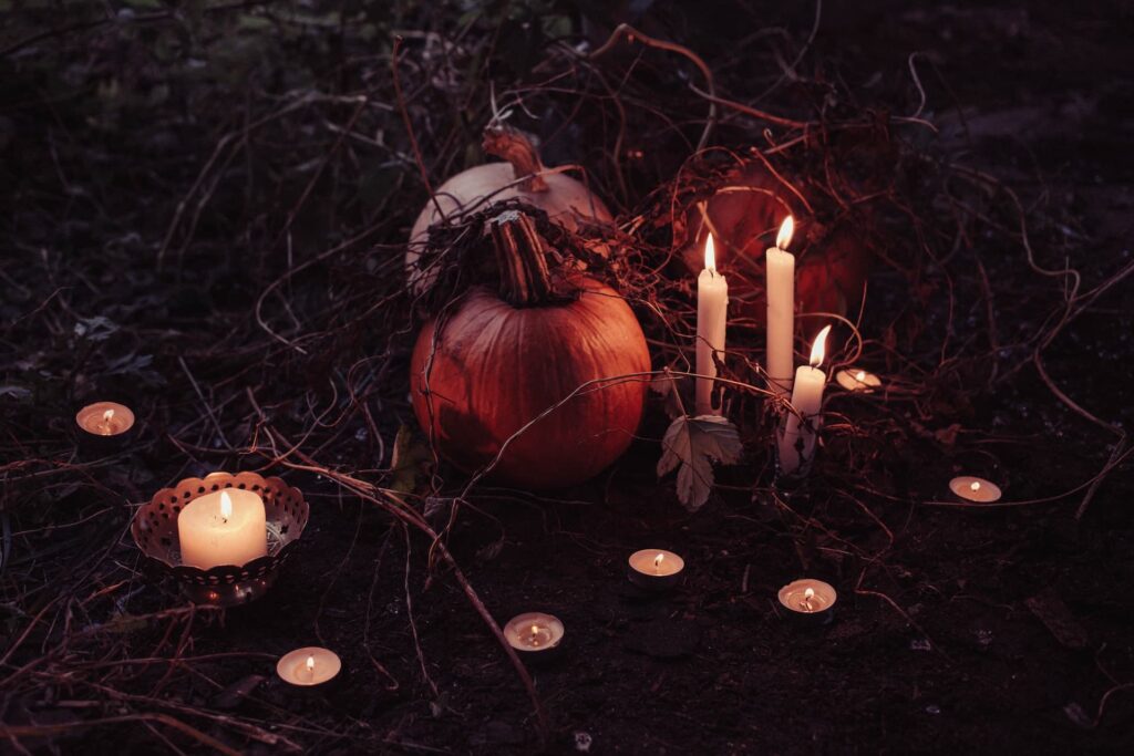 Fotografia de abóboras rodeadas por velas acesas em um ambiente escuro e misterioso, criando uma atmosfera perfeita para o Halloween. A imagem é ideal para promover as Festas de Halloween em Lisboa 2024, capturando o espírito sombrio e festivo da ocasião.