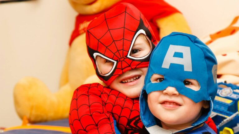 Fotografia de duas crianças sorridentes vestidas com fantasias de super-heróis, destacando um ambiente de diversão e imaginação. Ideal para promover teatro infantil em Lisboa, capturando a alegria e a criatividade das atividades teatrais para crianças.